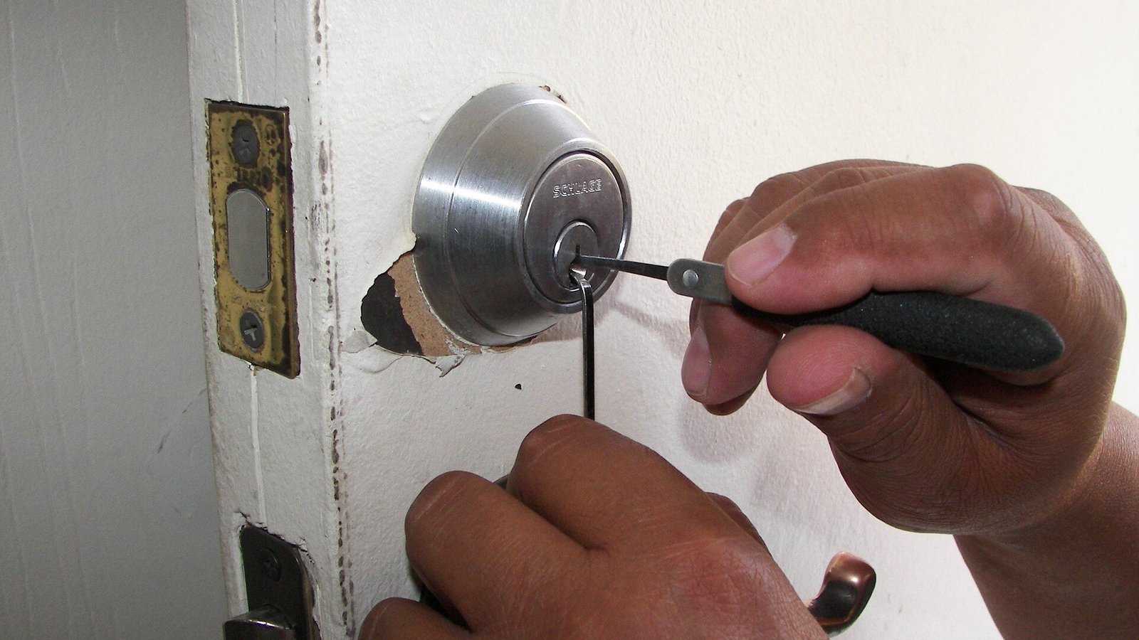 Manos de un cerrajero trabajando un bombín con un destornillador